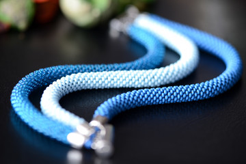Bead crochet bracelet of three shades of blue on a dark background close up