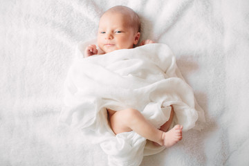 Cute newborn girl sleeping on furry cloth wearing white headband