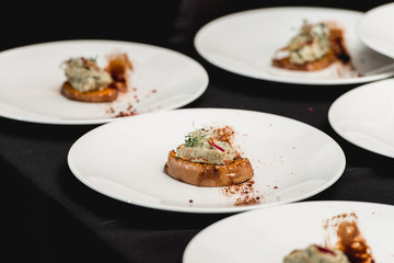 several white plates on a black table with baked sweet pumpkin and guacamole. Mexican cuisine at the restaurant