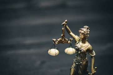 Scales of Justice, Justitia, Lady Justice on a black wooden background.
