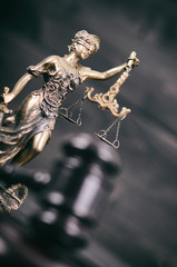 Scales of Justice, Judge Gavel, Justitia, Lady Justice on a black wooden background.