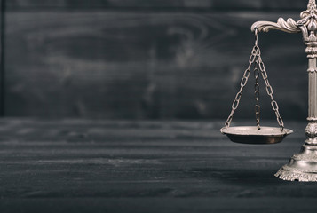  Scales of Justice on a black wooden background.