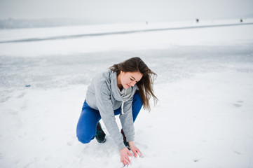 Funny girl wear on hoody sweater and jeans, at frozen lake in winter day.