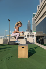 Fit young woman doing box jumping.