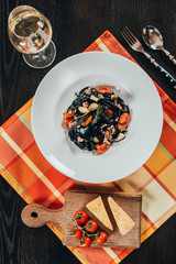 top view of spaghetti with cuttlefish ink, squid and octopus on plate