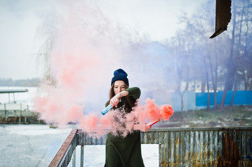 Young girl with blue and red colored smoke bomb in hands.