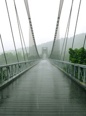 Sainte Rose / La Reunion: The magnificent and impressive old suspension bridge over the East River on a rainy day in January