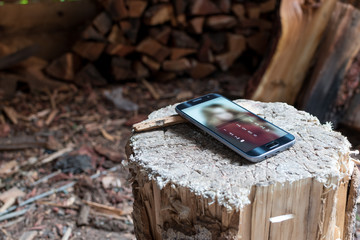 Smartphone on the stump. Firewood. Digits on the screen.