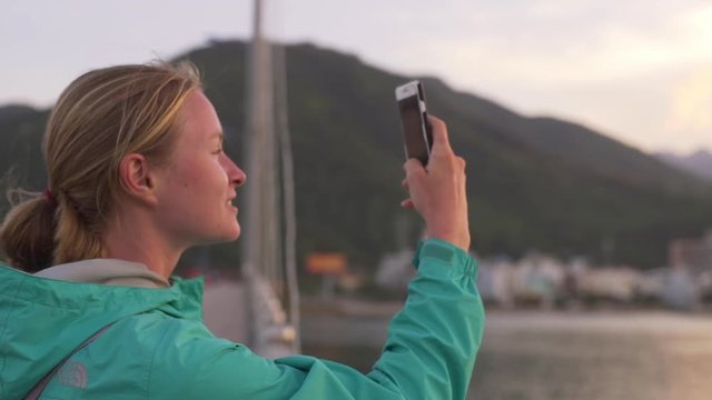 Blonde girl make photo on her smartphone from bridge at sunset rapid slow motion