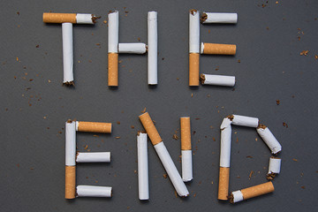 The end of smoking. Cigarettes cause cancer and kill. Gray background.