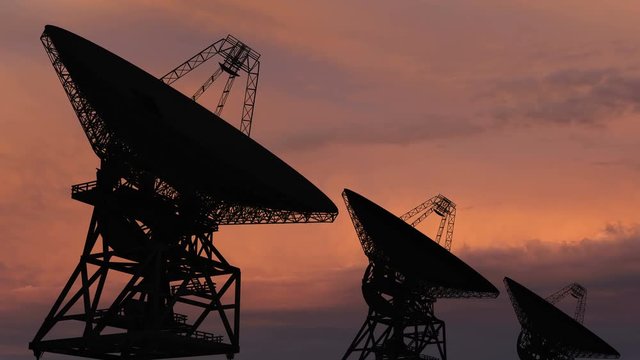 Satellite dishe moving in time-lapse against a sunset sky.