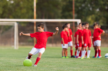 Boy kicking football on the sports field