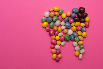 A tooth of sweets scattered on a pink background.