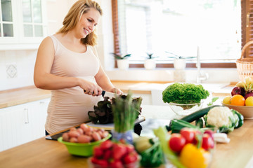 Obraz na płótnie Canvas Pregnant woman making a meal in kitchen