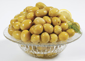 Green olives watered with oil in a glass glass on a white background
