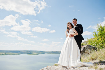 Wedding couple at breathtaking landscape with rock and lake.