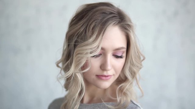 close-up portrait of an attractive blonde. young girl with a light make-up and curls