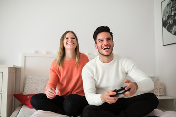 Fototapeta na wymiar Young couple playing video games in bed