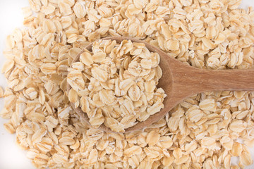 Plenty of organic oat flakes and full wooden spoon in top view. 