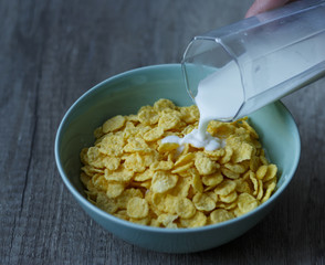 from a glass pour milk in a green plate a plate of flakes that stands on a wooden table