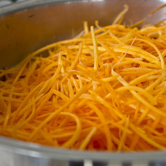 Shredded carrots in a professional large steel pan