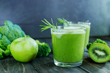 Green smoothies with kiwi, apple and broccoli on a wooden table