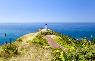 Fototapeta na wymiar Stunning wide angle view of Cape Reinga Lighthouse and the path leading to it at Cape Reinga, the northernmost point of the North Island of New Zealand. The lighthouse is a famous tourist attraction.
