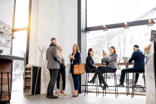 Business people having a conversation during the coffee break near the window in the cafe