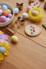 Fototapeta na wymiar Easter background. Multicolored choccolate eggs, cookies in shape of bunny, bell and egg,and decoration on wooden table 