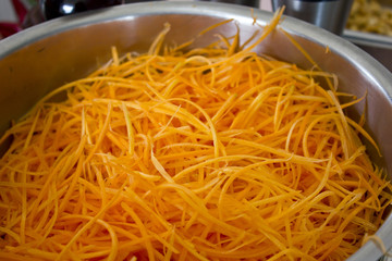 Shredded carrots in a professional large steel pan