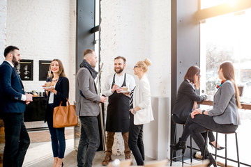 Business people having a conversation during the coffee break standing with waiter in the cafe