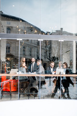Business people during the coffee break sitting with laptops near the window. General view through the window with city reflection and copy space