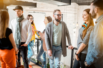 Group of friends dressed casually talking together during the coffee break standing in the white conference hall