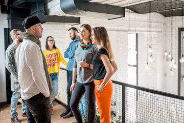 Group of friends dressed casually talking together during the coffee break standing in the white conference hall