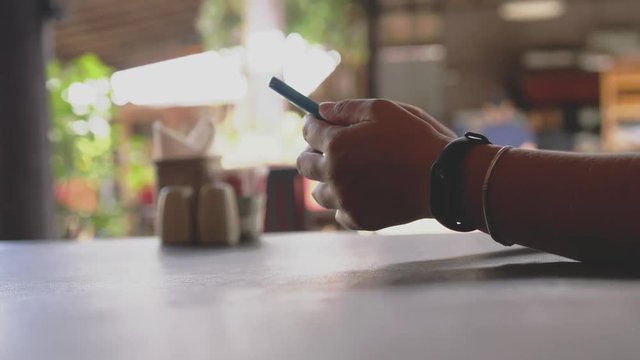 Close up of female hands wearing clock with pedometer scrolling smart phone, surfing internet, in cafe with blurred bokeh. 3840x2160, 4k