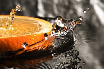 an orange ring with splashes of water, a fruit with splashes