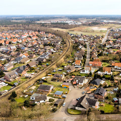 Aerial view of a small village in Lower Saxony, which is cut up by a single-lane railway line.