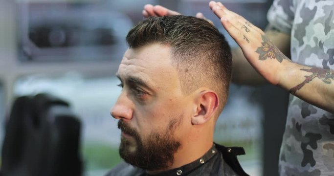 Hairdresser is applying gel on the hair of customer in barbershop.
