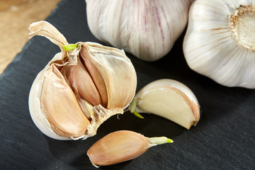 Garlic close up on wooden plate on rustic background, shallow depth of field, selective focus, macro
