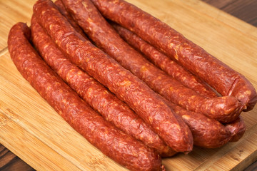 Thin smoked sausage on a wooden background. Close-up.