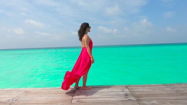 Woman in Red Dress admiring the Tropical Landscape in Maldives in Slow Motion