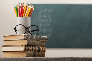 Stack of books and school blackboard