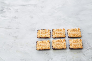 Square biscuits arranged in pattern on light textured background, close-up, shallow depth of field, selective focus.