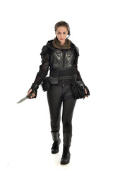 Fototapeta premium full length portrait of female soldier wearing black tactical armour, holding a remote knife, isolated on white studio background.