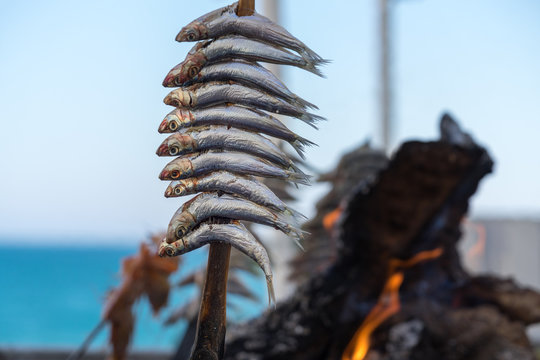 an Holzkohle gegrillte Sardinen mit Flammen und gl&uuml;hender Kohle imHintergrund
