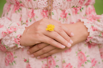 Young woman hand wearing Yellow flower represent of wedding ring on grass green background. Broken hearted, Love forever, Wedding and Valentines day concept.