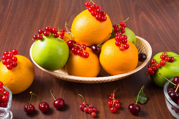 Fruits and berries. Apple, orange, cherry and currant on wooden table.