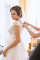 Beautiful young bride in wedding dress in living room