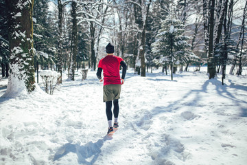 Young man running at winter in park