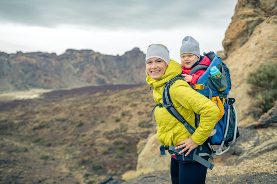 Happy mother with little boy travelling in backpack
